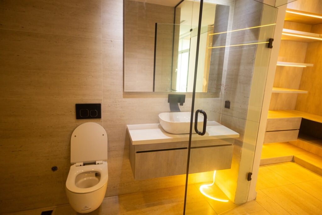 Brum Height 6: Bathroom vanity and toilet beside an illuminated wardrobe area